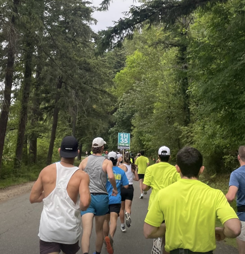 runners on a tree-lined course, following the 1:35 half-marathon pacer